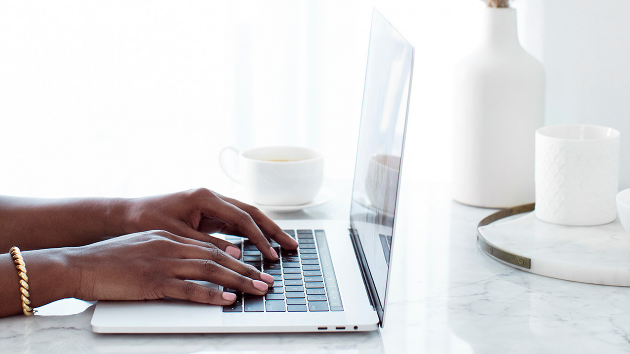 A woman's hands resting on a laptop keyboard